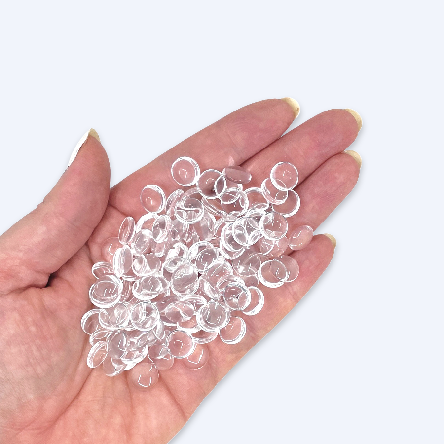 Glascabochoner i handen illustrerar storleken, 10 mm diameter, klart glas