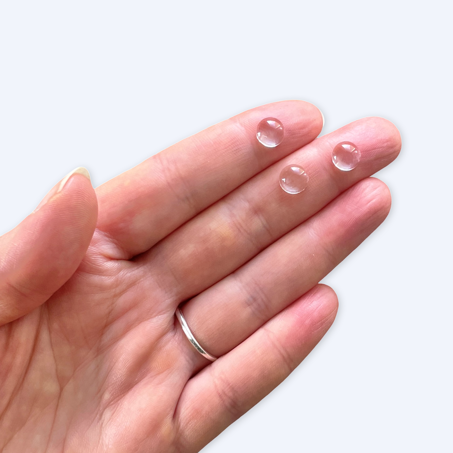 Glasscabochoner utspridda på vit bakgrund, 8 mm konvexa klara cabochoner, glas
