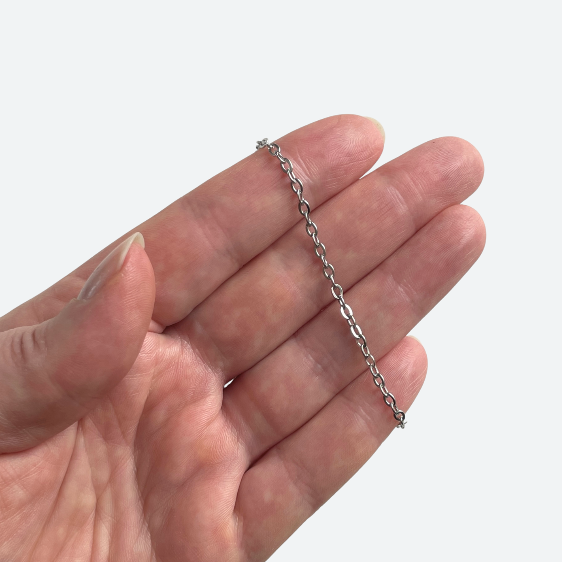 Tillplattad ankarlänkskedja hänger i handen som användningsexempel, 3,5 x 2,5 mm rostfritt stål